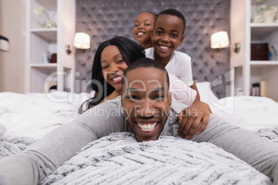 Portrait of happy man lying with family on bed