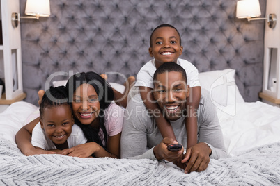 Portrait of happy family watching television while lying on bed