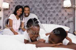 Happy couple sitting with children lying in foreground