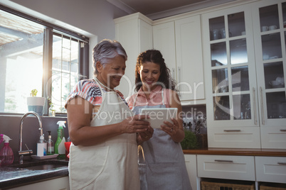 Mother and daughter using digital tablet in kitchen