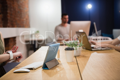 Female executive adjusting smart watch at desk