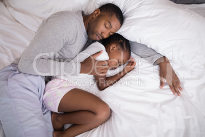 Father and daughter sleeping on bed at home