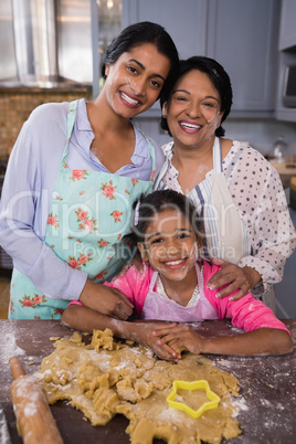 Portrait of smiling multi-generation family standing by dough in kitchen