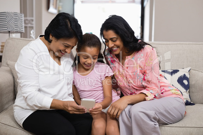 Happy multi-generation family using mobile phone together at home