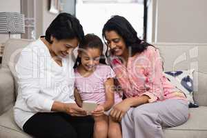 Happy multi-generation family using mobile phone together at home