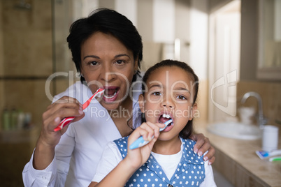 Smiling girl and grandmother brushing teeth in bathroom