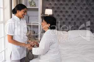 Smiling nurse comforting mature woman on bed