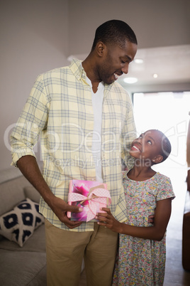 Happy father and daughter holding gift box at home