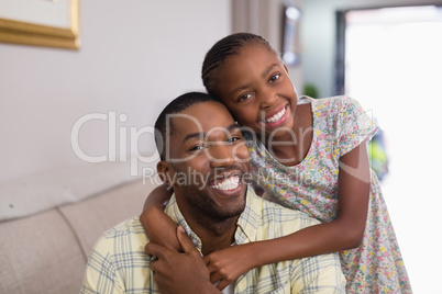 Portrait of happy father and daughter in living room