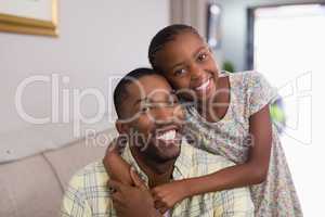 Portrait of happy father and daughter in living room