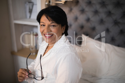 Smiling mature woman sitting on bed at home