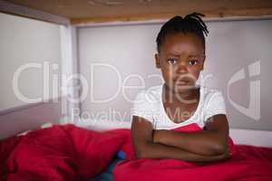 Portrait of upset little girl sitting on bed