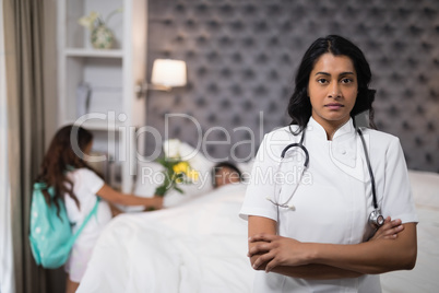 Serious nurse standing with patient on bed at home