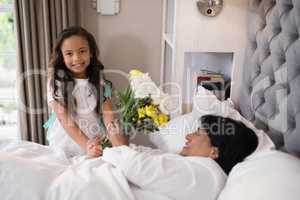 Portrait of girl giving bouquet to sick grandmother at home