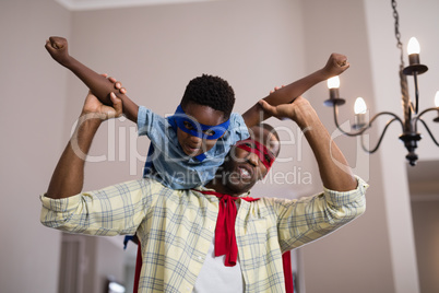 Father and son wearing superhero costume at home