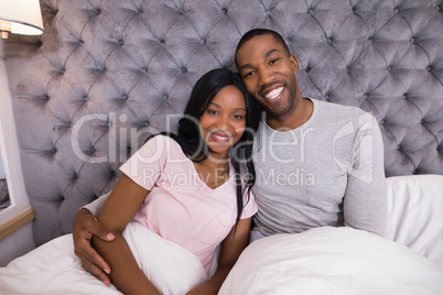 Portrait of smiling couple sitting together on bed
