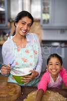 Portrait of smiling girl preparing food with mother at home