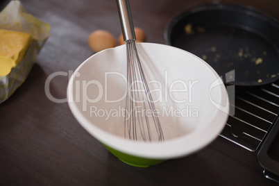 High angle view of bowl with wire whisk in kitchen