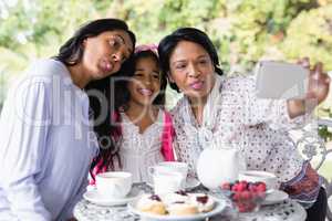 Multi-generation family taking selfie while sitting together by breakfast table