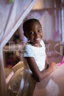 Cheerful girl wearing crown while standing at home