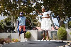 Siblings in costumes jumping on trampoline