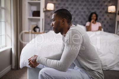 Young man siting while woman resting on bed at home