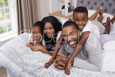 Portrait of happy family lying together in bedroom