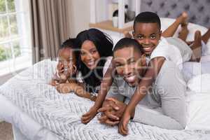 Portrait of happy family lying together in bedroom
