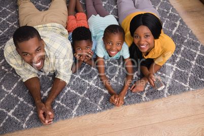 Portrait of smiling family lying on rug at home