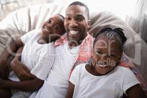 High angle portrait of happy father with daughter and son resting on couch