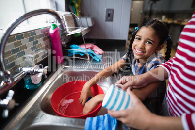 Portrait of cute girl helping her mother in kitchen