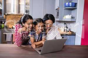 Smiling multi-generation family using laptop in kitchen