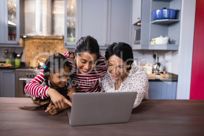 Happy multi-generation family using laptop in kitchen