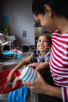 Cute smiling girl helping her mother in kitchen