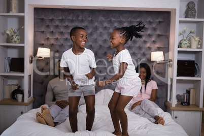 Playful siblings jumping on bed