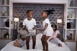 Playful siblings jumping on bed