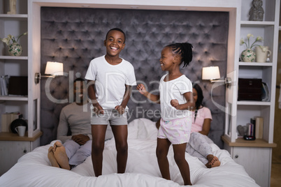 Happy siblings jumping on bed