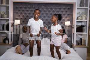 Happy siblings jumping on bed