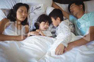 Family sleeping on bed in the bed room