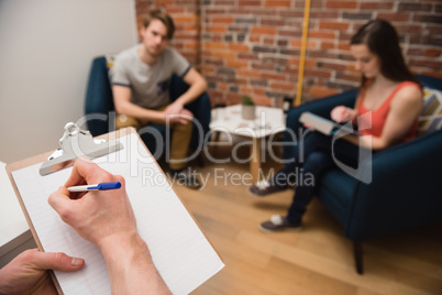 Executive writing on clipboard in office