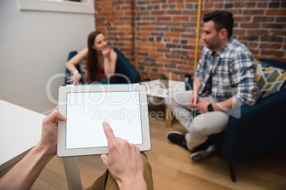 Executive using digital tablet and colleagues discussing in background