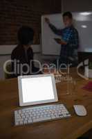 Digital tablet on table while colleague discussing in background