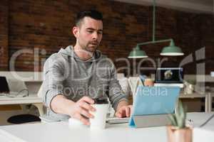 Male executive working on digital tablet while having coffee