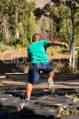 Boy running over tyres during obstacle course training