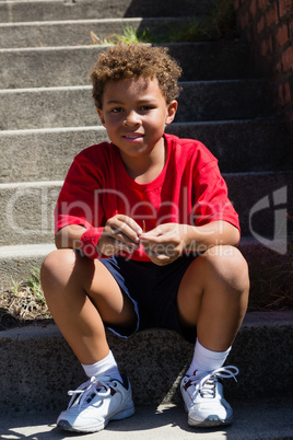 Boy sitting on staircase in the boot camp on a sunny day