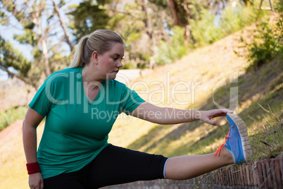 Woman performing stretching exercise during obstacle course training