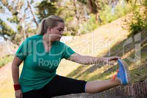 Woman performing stretching exercise during obstacle course training