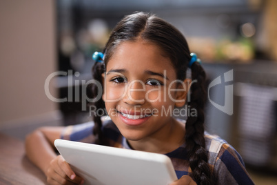 Portrait of girl holding digital tablet at home