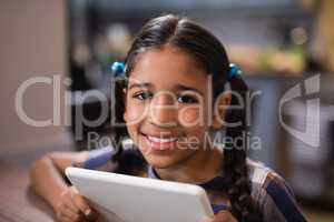 Portrait of girl holding digital tablet at home