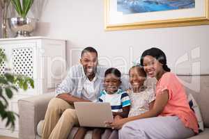 Happy family using laptop on sofa at home